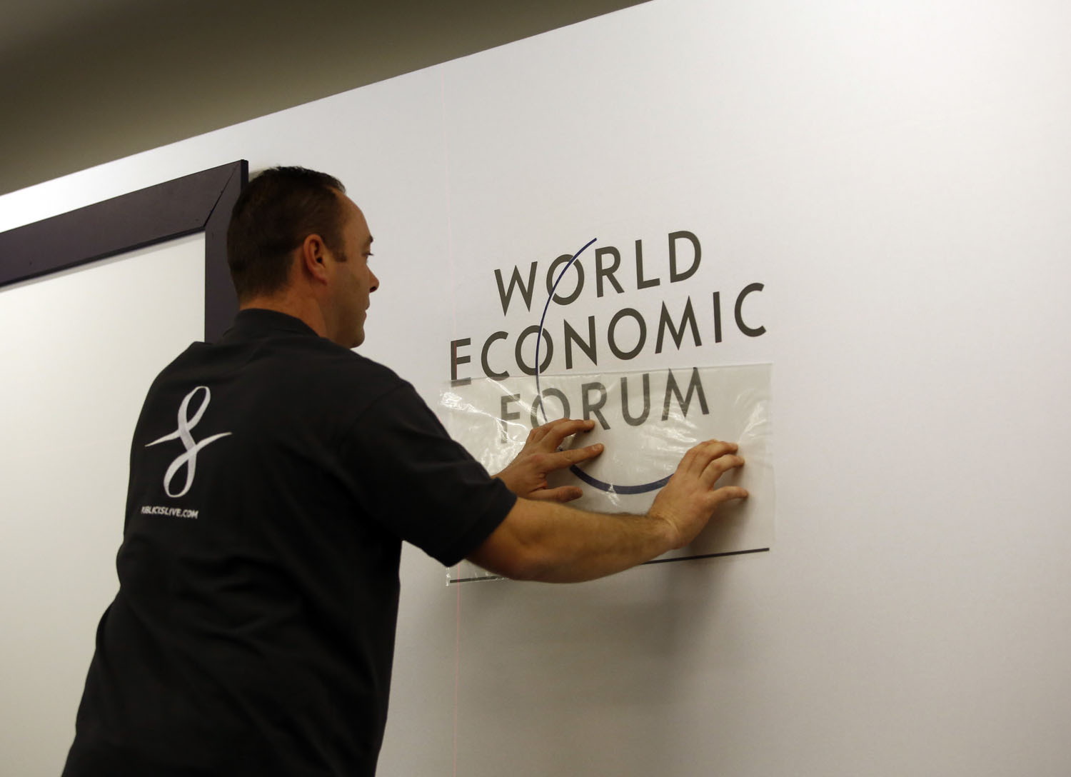 A worker prepares a logo for the World Economic Forum inside the Congress Center ahead of the World Economic Forum 2014 (WEF) meeting in Davos, Switzerland, on Sunday, Jan. 19, 2014.