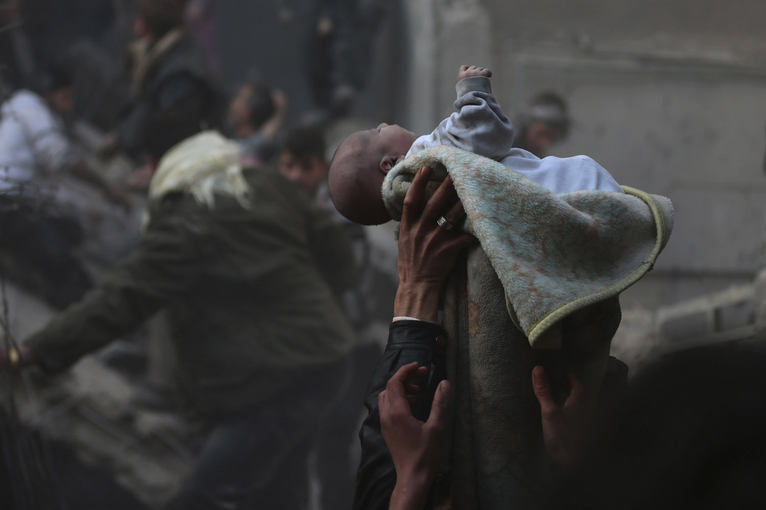 Men hold up a baby saved from under rubble, who survived an airstrike in the Duma neighbourhood of Damascus