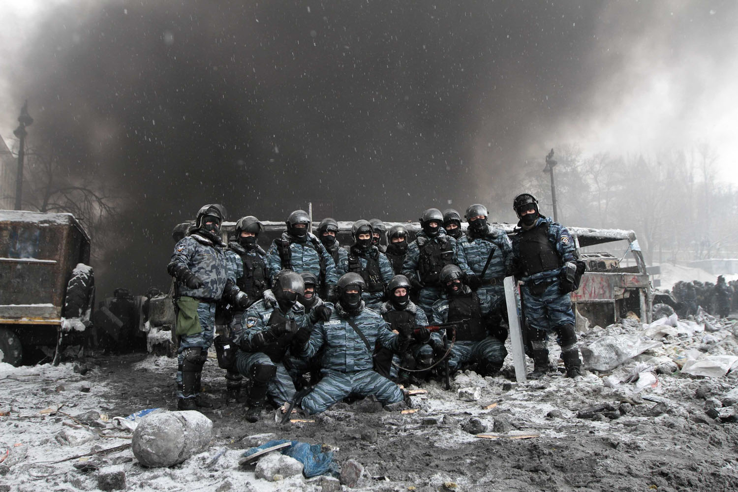 Jan. 22, 2014. Riot police officers pose for a picture near burnt vehicles as smoke rises in the background during clashes with pro-European protesters in Kiev, Ukraine.