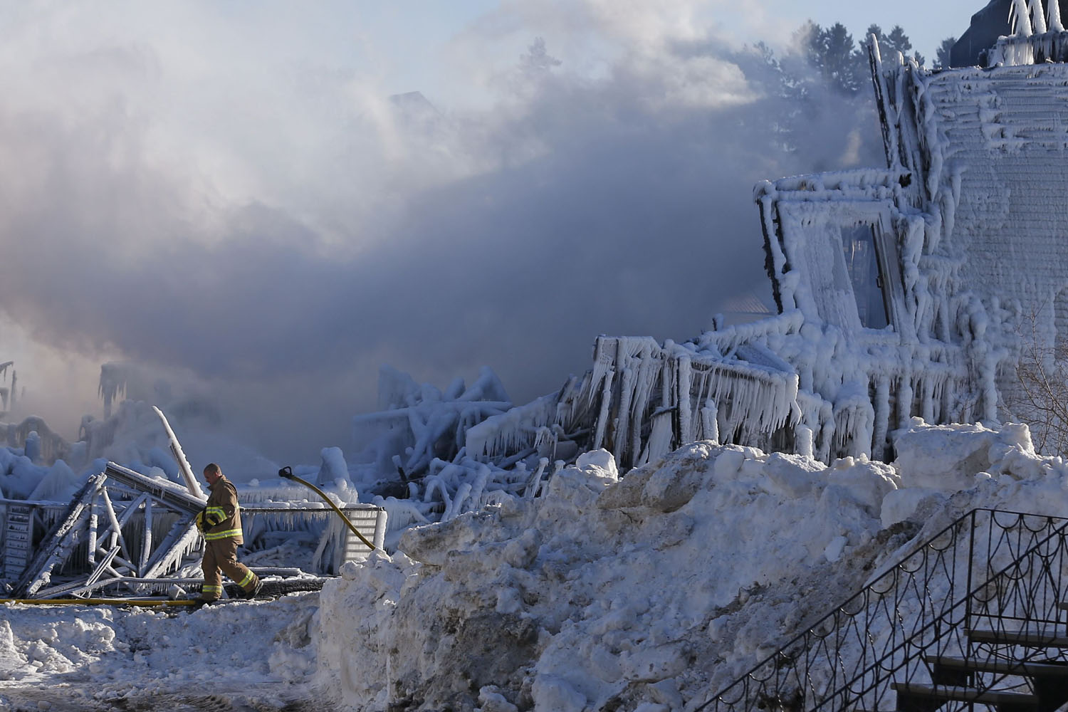 Jan. 23, 2014. A firefighter walks past the Residence du Havre after a fire in L'Isle Verte, Quebec, Canada.