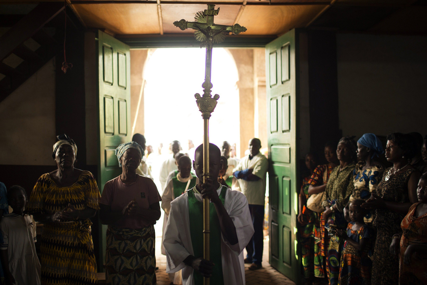 A boy carries a cross at the beginning of Sunday mass in a church in Wango