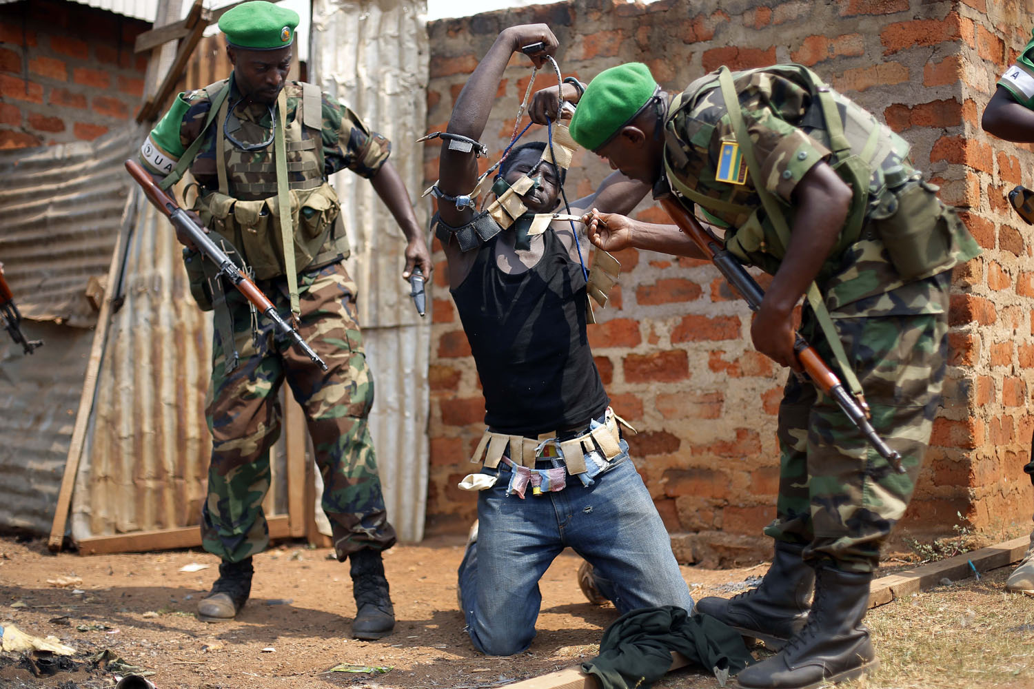 Jan. 22, 2014. Rwandan African Union peacekeepers remove the lucky charms from a suspected Anti-Balaka Christian man who was found with a rifle and a grenade following looting in the Muslim market of the PK13 district of Bangui, Central African Republic.