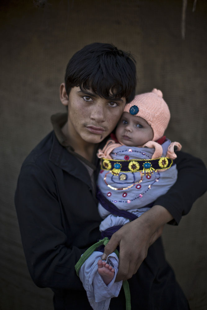 Shahzada Saleem, 15, holds his nephew Satara, two months, as they pose for a picture in a slum on the outskirts of Islamabad, Pakistan on Jan. 25, 2014.