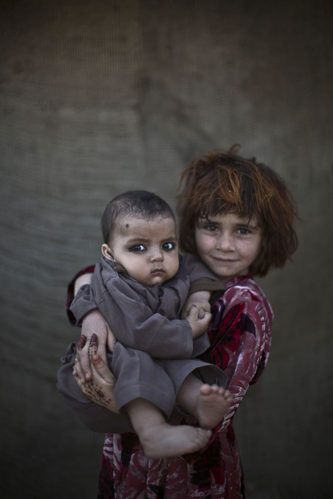 Khalzarin Zirgul, 6, holds her cousin, Zaman, 3 months, as they pose for a picture while playing with other children in a slum on the outskirts of Islamabad, Pakistan on Jan. 27, 2014.
