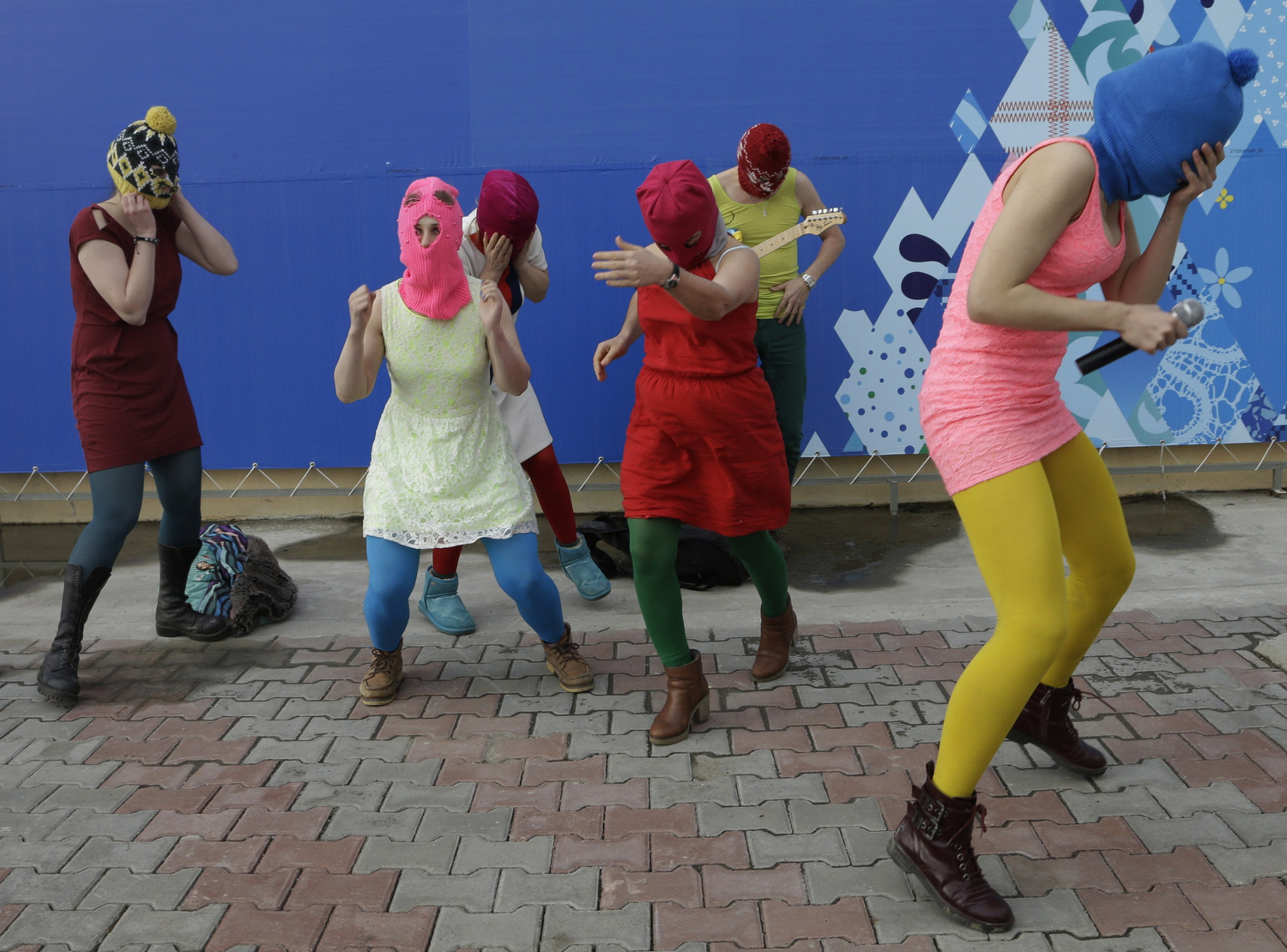 Nadezhda Tolokonnikova covers her face to protect herself from a Cossack militiaman while she and fellow members of the punk group Pussy Riot, including Maria Alekhina, second left, in the pink balaclava, stage a protest performance in Sochi, Russia, on Wednesday, Feb. 19, 2014.