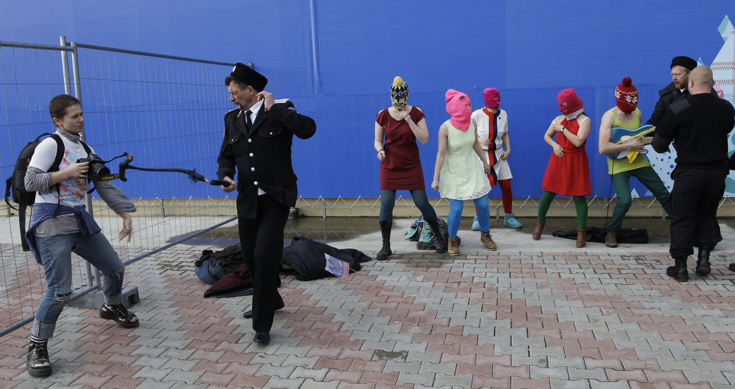 A photographer is whipped by a member of the Cossack militia while trying to photograph members of the punk group Pussy Riot being attacked by Cossack militia and a Russian security officer, in Sochi, Russia, on Wednesday, Feb. 19, 2014.