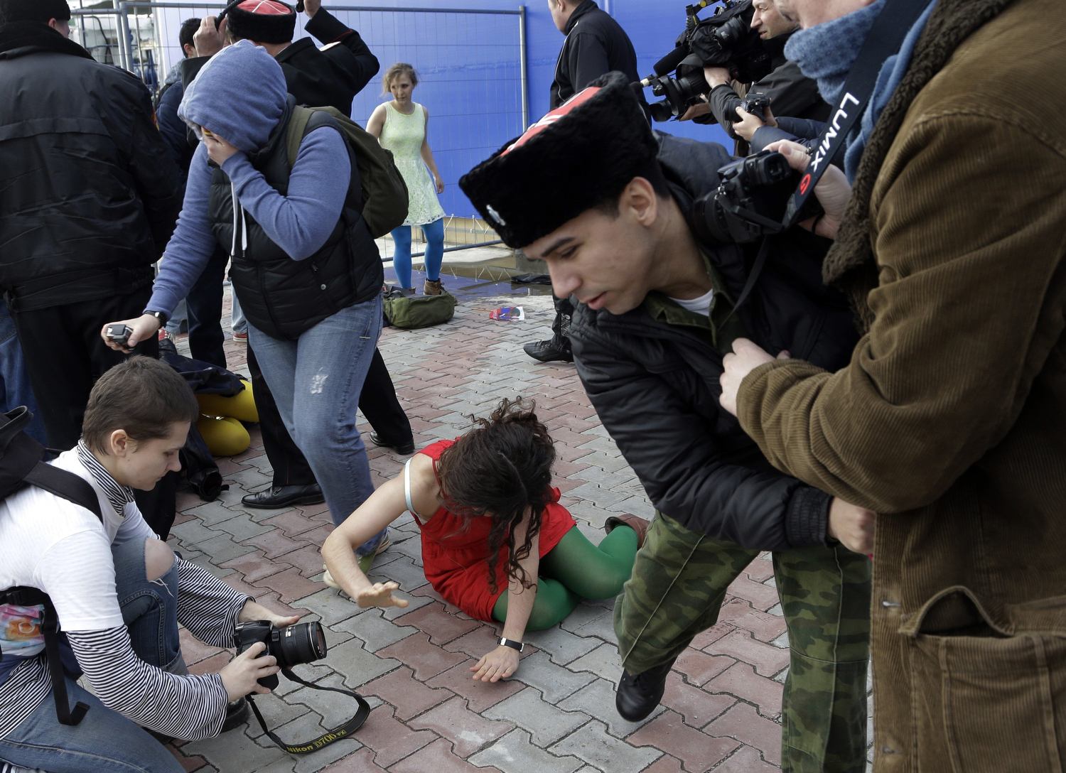 A member of the punk group Pussy Riot lies on the ground as the group are attacked by Cossack militia in Sochi, Russia, on Wednesday, Feb. 19, 2014.