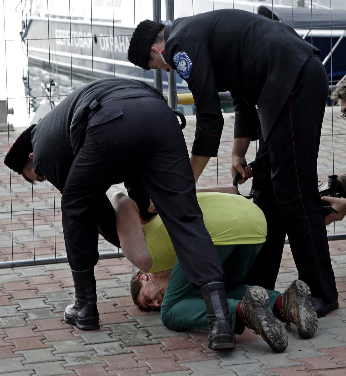 A member of the punk group Pussy Riot is restrained by Cossack militia after the group tried to perform in Sochi, Russia, on Wednesday, Feb. 19, 2014. The group had gathered in a downtown Sochi restaurant, about 30km (21miles) from where the Winter Olympics are being held. They left the restaurant wearing bright dresses and ski masks and had only been performing for a few seconds when they were set upon by Cossacks. (AP Photo/Morry Gash)