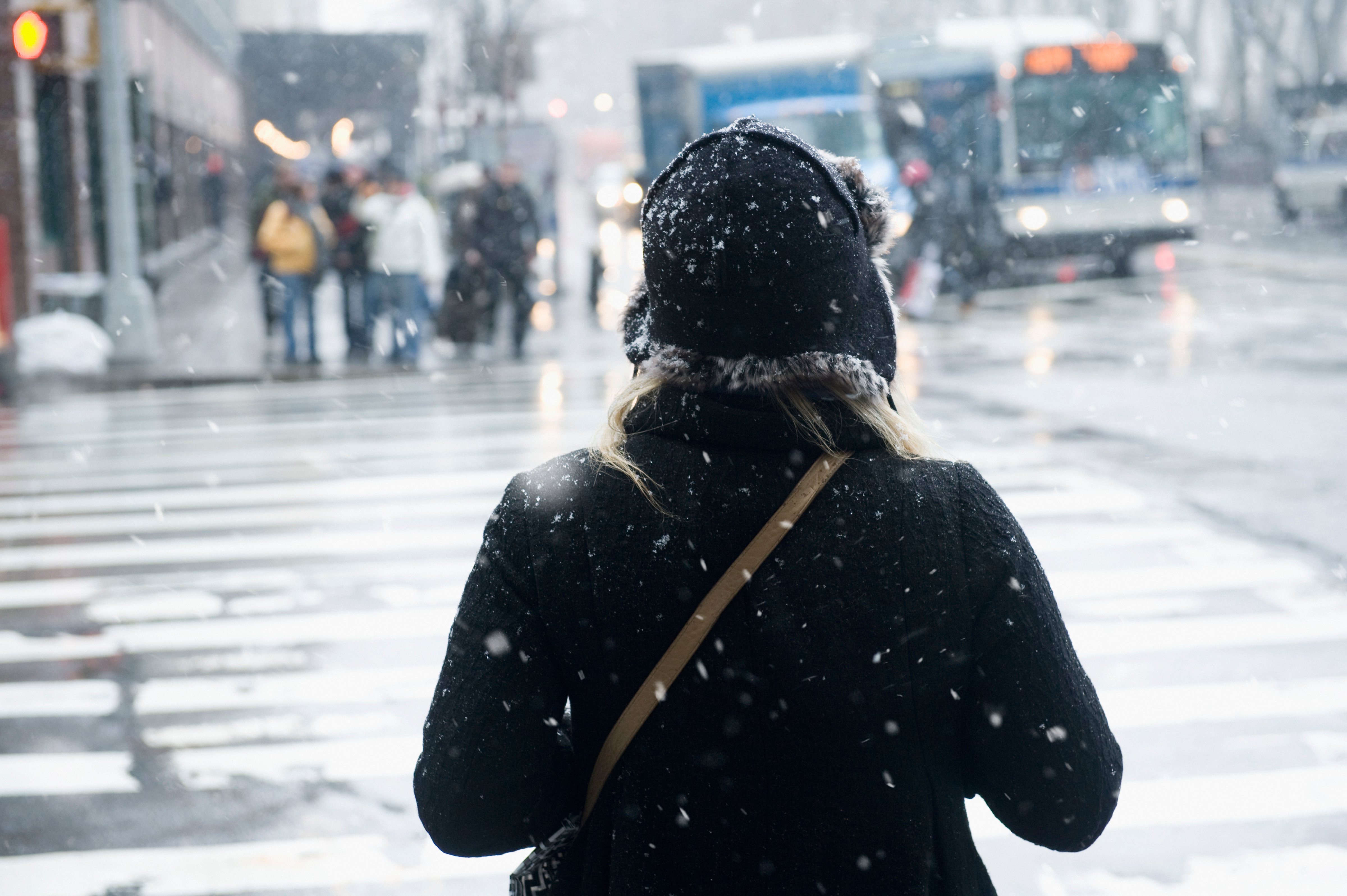 Young woman about to cross the street in snow