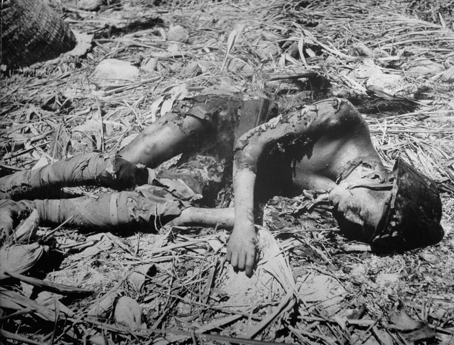Caption from back of the print of this photograph in the LIFE archives: "Dead Jap [sic] with smoke still rising from his stomach where flamethrower boiled him open."