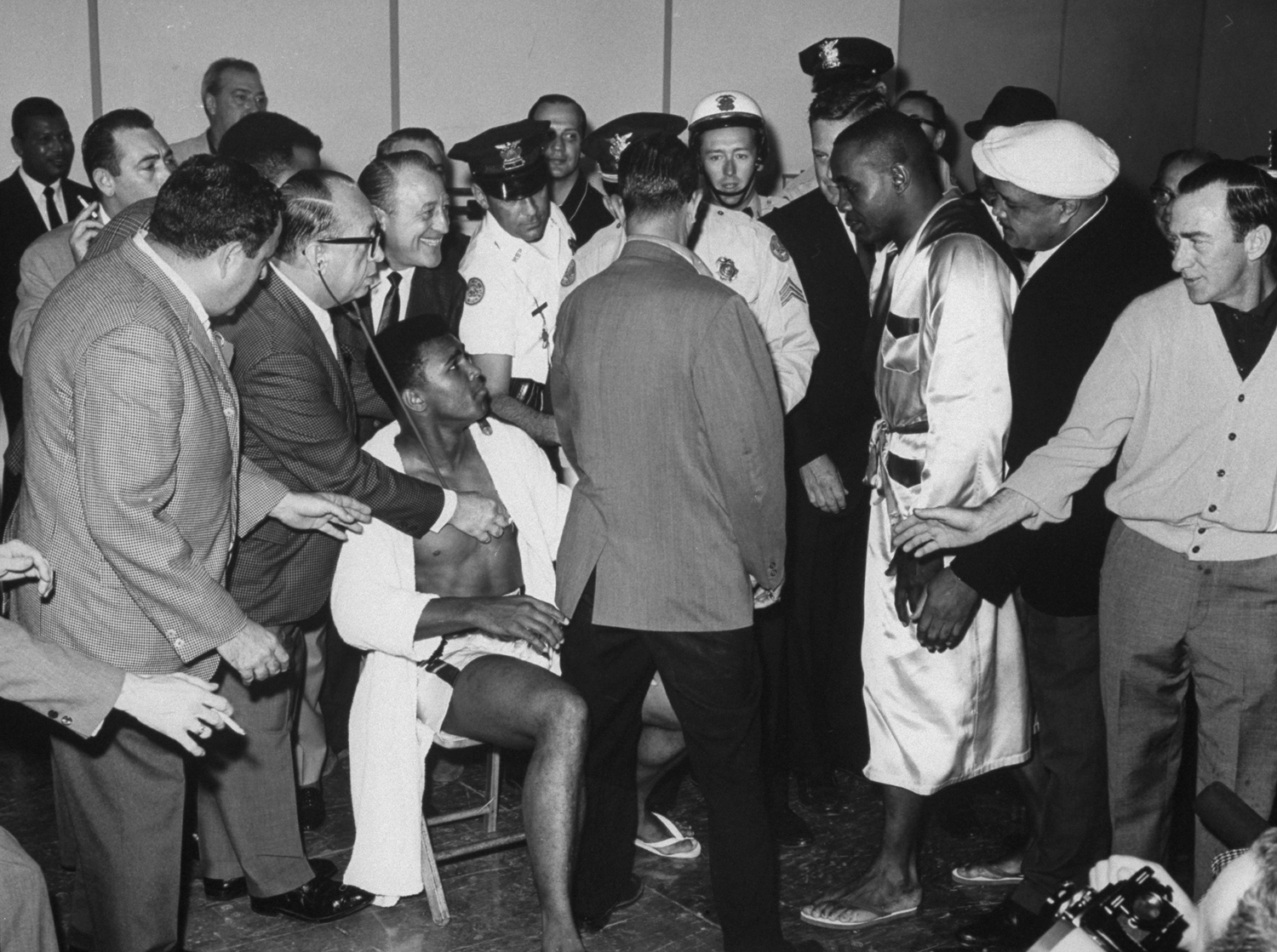 Sonny Liston at the weighting-in ceremonies before his heavyweight championship fight with Cassius Clay (sitting at left).