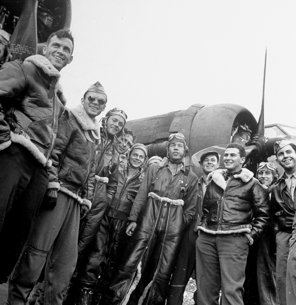 Jubilant B-17 crew members pose next to their plane upon returning to England unscathed after a bombing run, 1942.