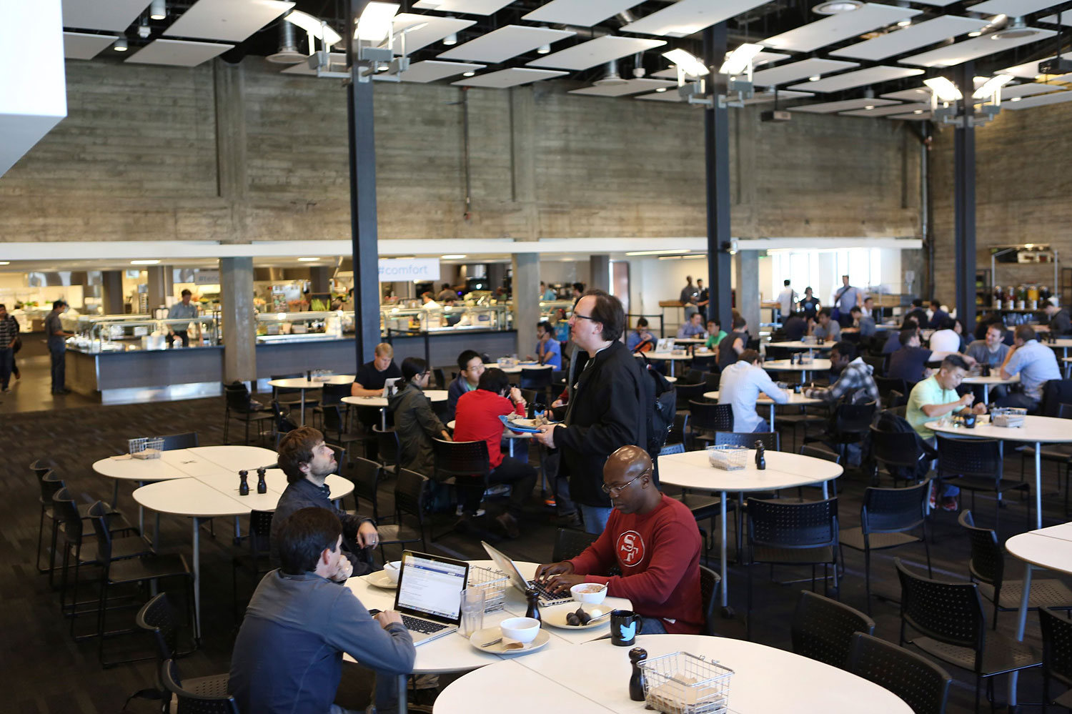 Twitter employees sit in a cafeteria at the company's headquarters in San Francisco, Oct. 4, 2013.