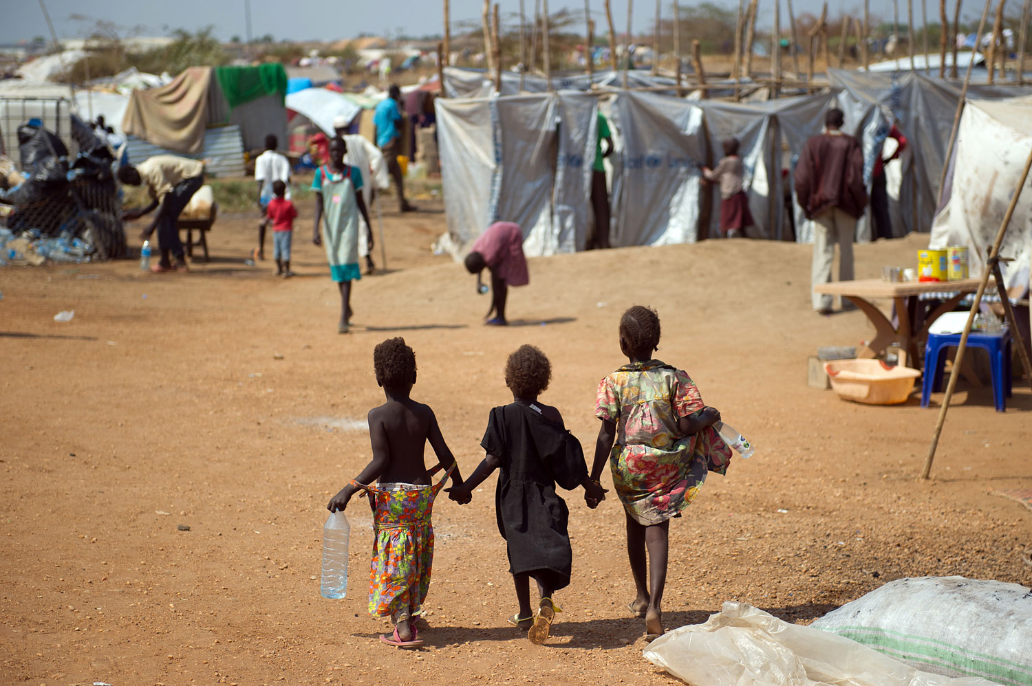 Three children walk through a spontaneous camp for internally displaced persons at the United Nations Mission to South Sudan base in Juba, on Jan. 9, 2014.