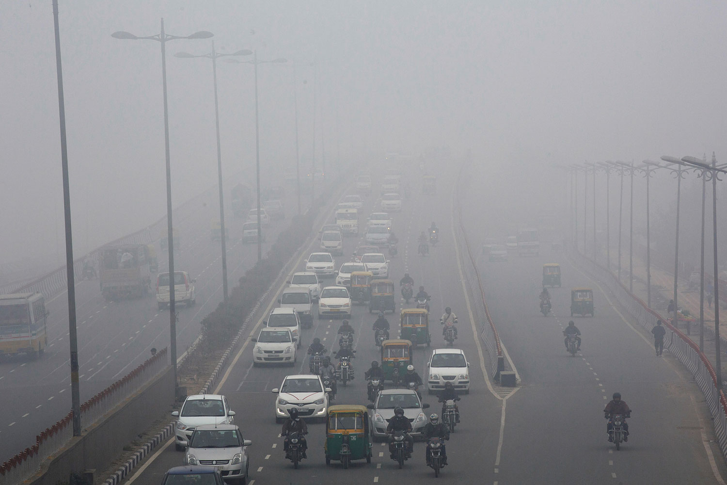 Traffic make way in haze mainly caused by air pollution in Delhi, on Jan. 20, 2014.