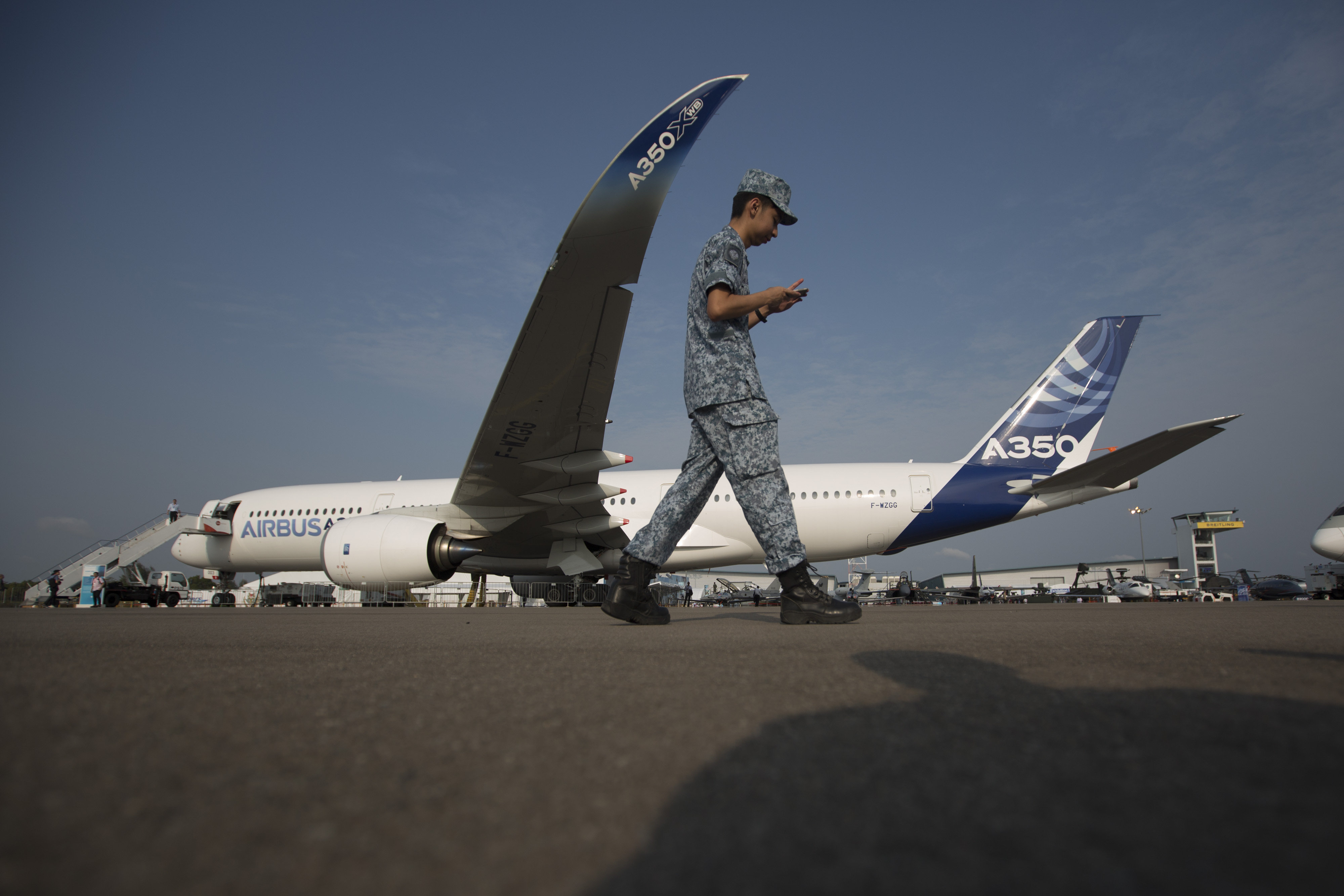 A soldier walks past an Airbus SAS A350 XWB flight test aircraft (MSN3) displayed at the Singapore Airshow held at the Changi Exhibition Centre in Singapore, on Feb. 11, 2014. (Brent Lewin—Bloomberg/Getty Images)