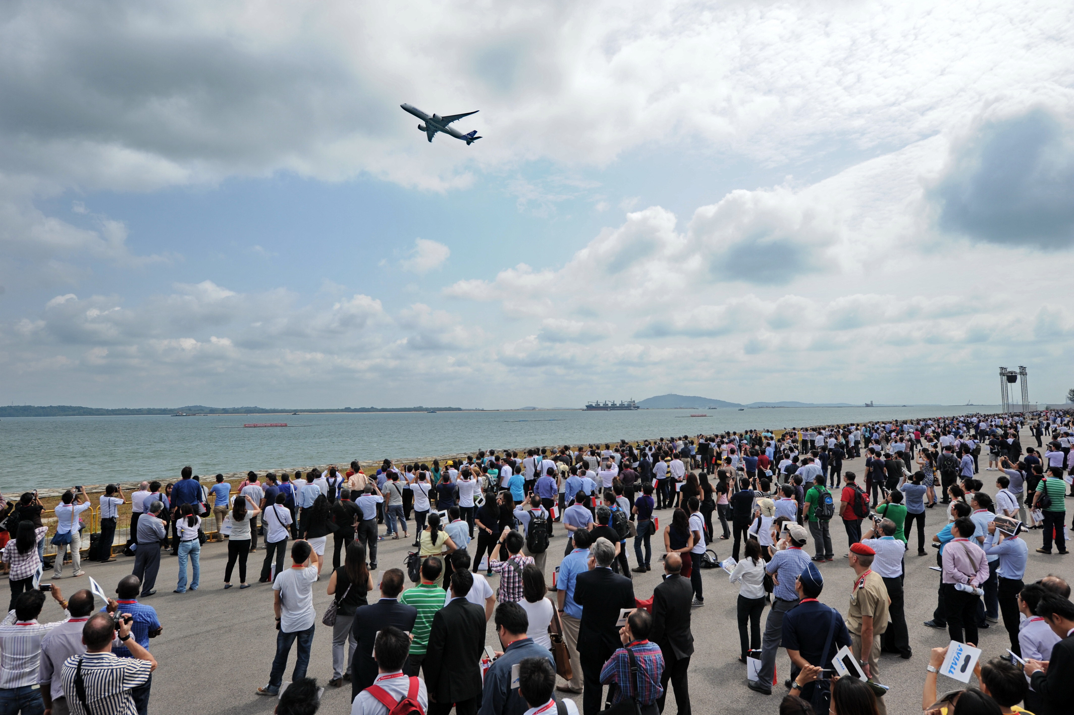 Visitors watch as a Airbus A350 flies past during the Singapore Airshow on Feb. 12, 2014.