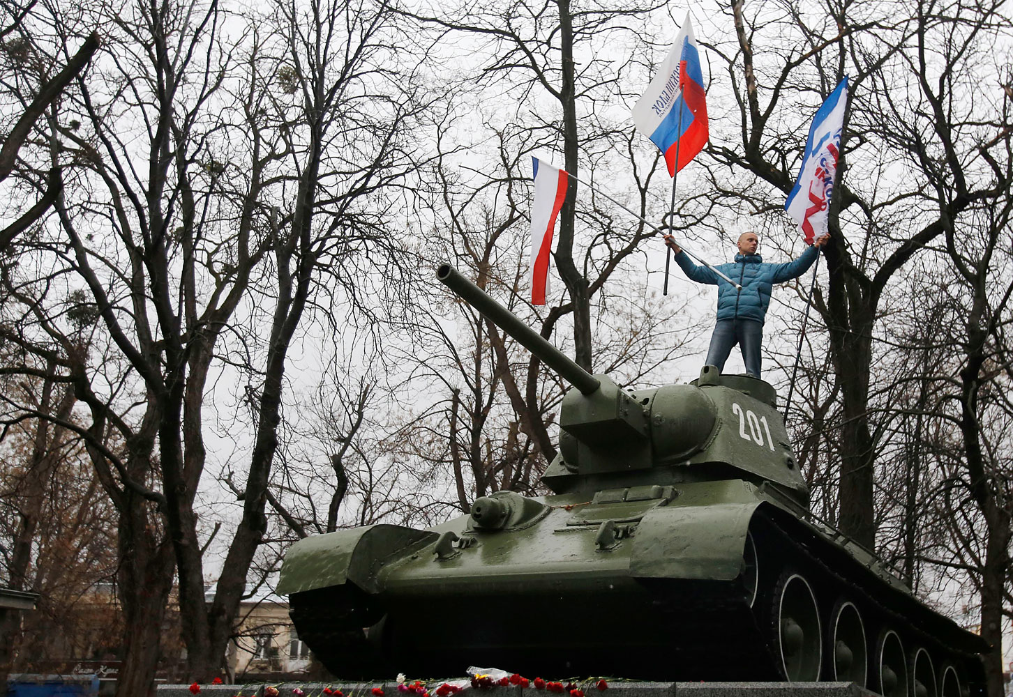 A Pro-Russian demonstrator waves Russian and Crimea flags atop an old Soviet Army tank during a protest in front of a local government building in Simferopol, Crimea, Ukraine, Feb. 27, 2014. (Darko Vojinovic—AP)