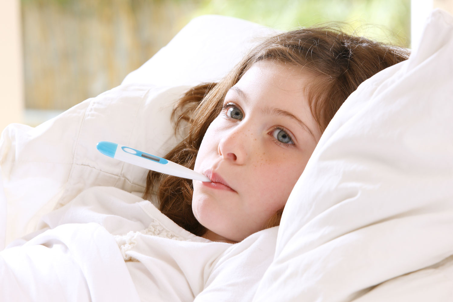 Girl in bed with thermometer in mouth