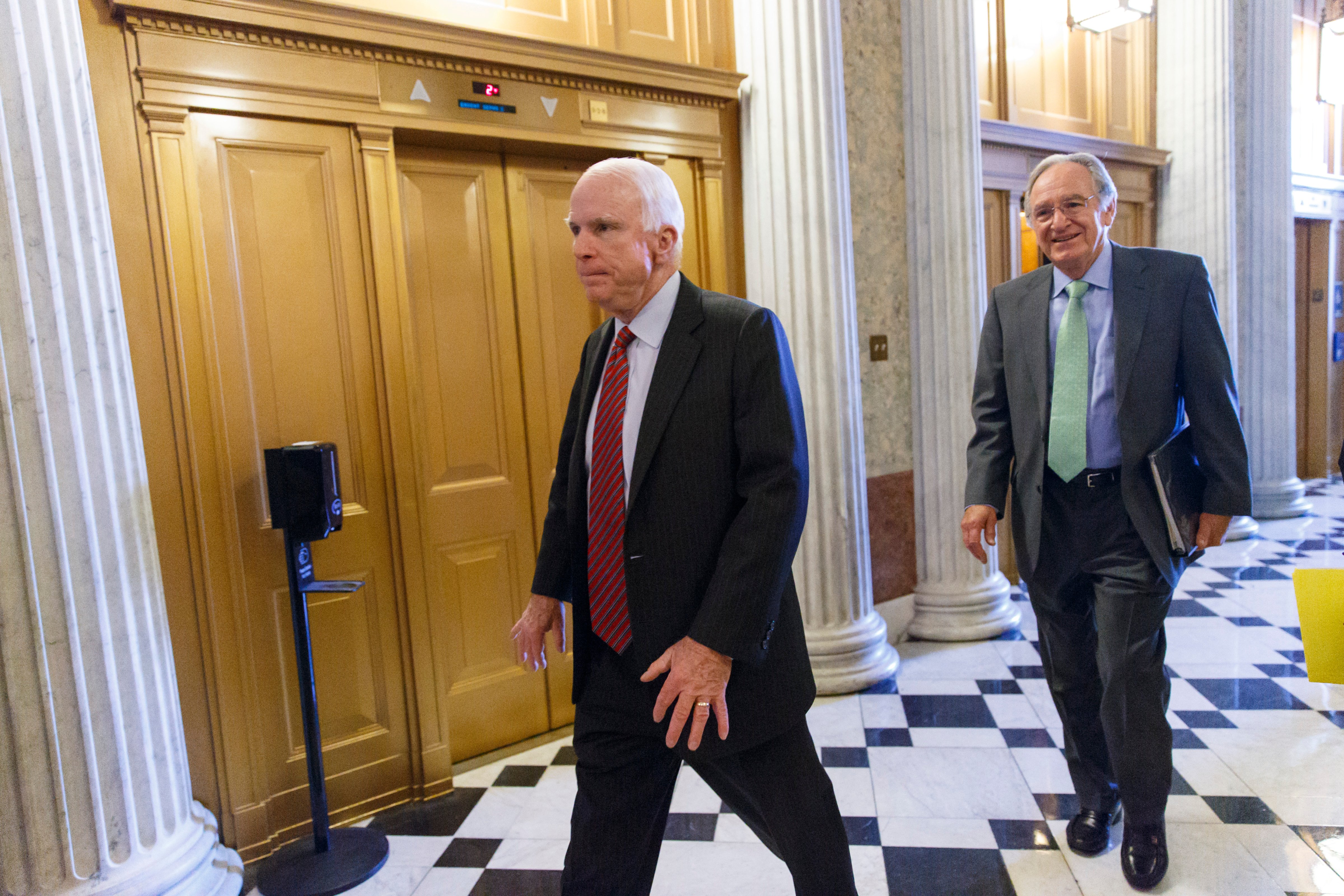 Sen. John McCain, R-Ariz., left, and Sen. Tom Harkin, D-Iowa, right, and other senators come and go from the chamber during votes at the Capitol in Washington, Tuesday, Feb. 25, 2014. (J. Scott Applewhite—AP)