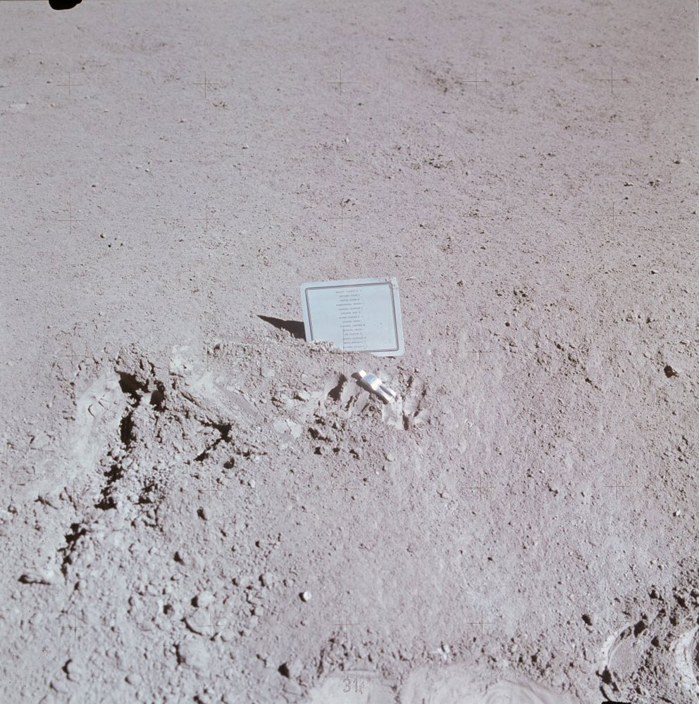 Dave Scott created a small memorial at the rover's final parking place to honor the astronauts and cosmonauts who had died prior to Apollo 15. The card lists the names. The figurine, Fallen Astronaut, was created by Belgian artist Paul van Hoeydonck. The imprints of Dave's fingers show up next to the figurine.