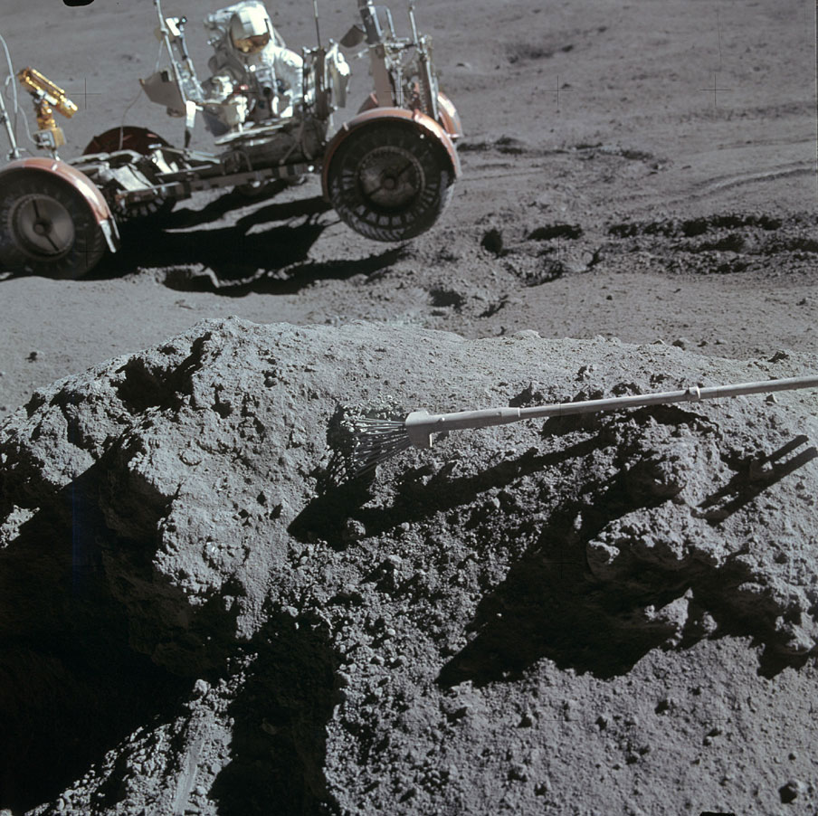Scott rested his sample tongs atop a rock to photograph Irwin near the rover. On the moon's irregular surface, at least one wheel—and sometimes two—were off the ground.