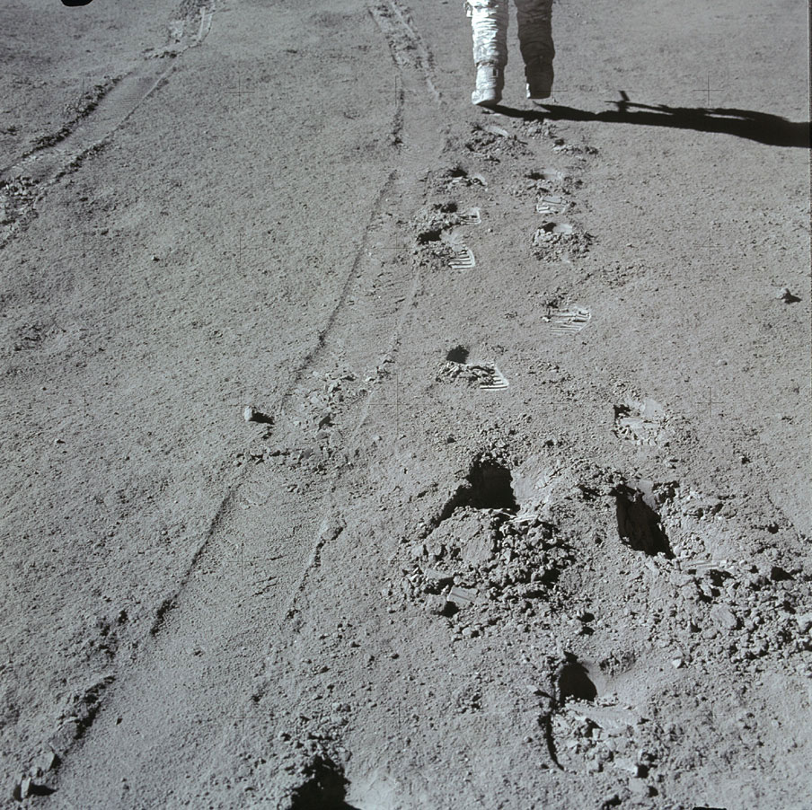 Apollo 15 was the first of three missions to include the lunar rover. Here, Irwin hikes ahead as Scott photographs him. Both footprints and wheel tracks are visible in the soil. They remain today.