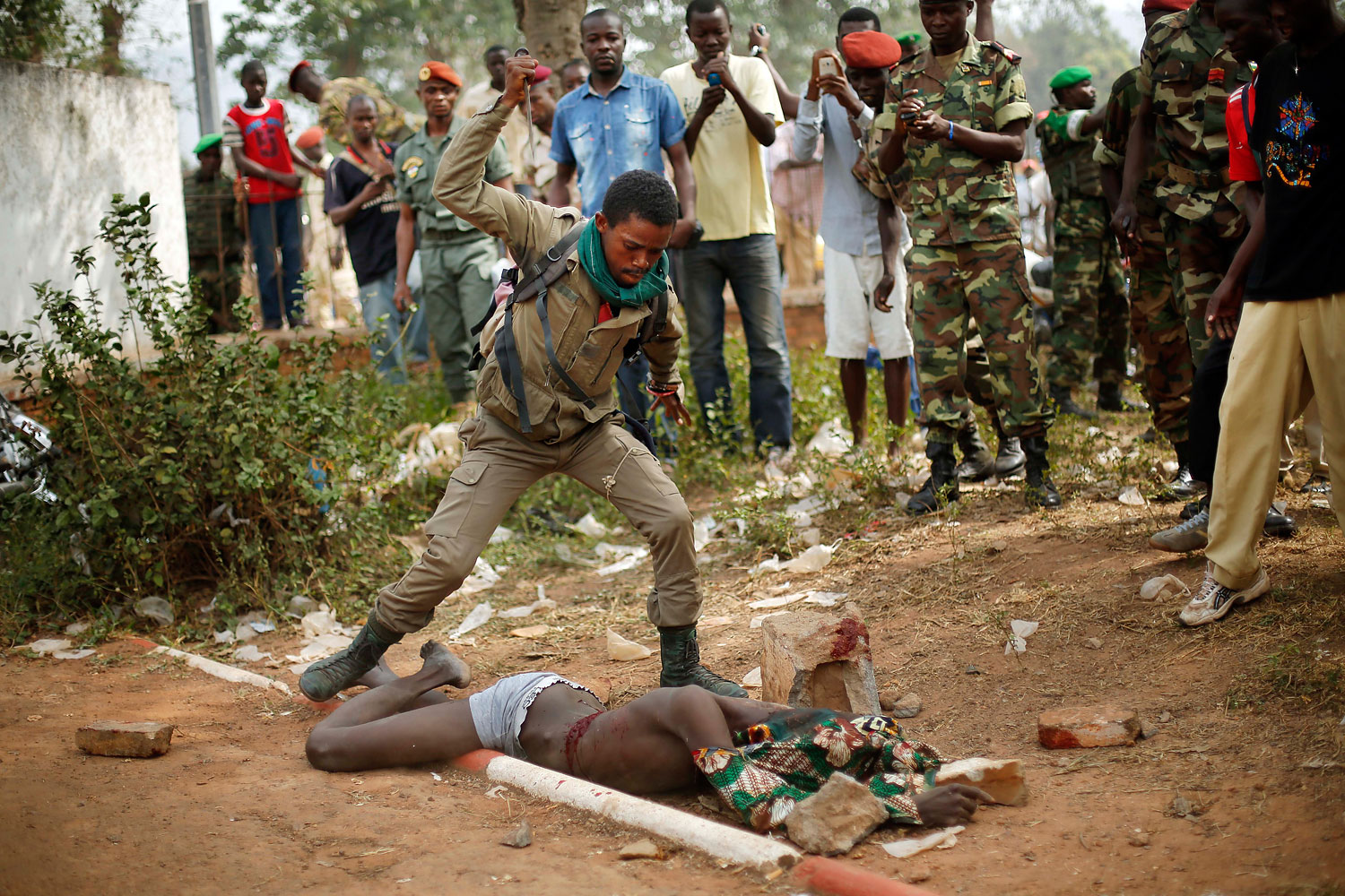 A newly enlisted Central African Armed Forces soldier stabs the lifeless body of a suspected Muslim Seleka militiaman moments after Central African Republic Interim President Catherine Samba-Panza addressed the troops in Bangui, Feb. 5, 2014.