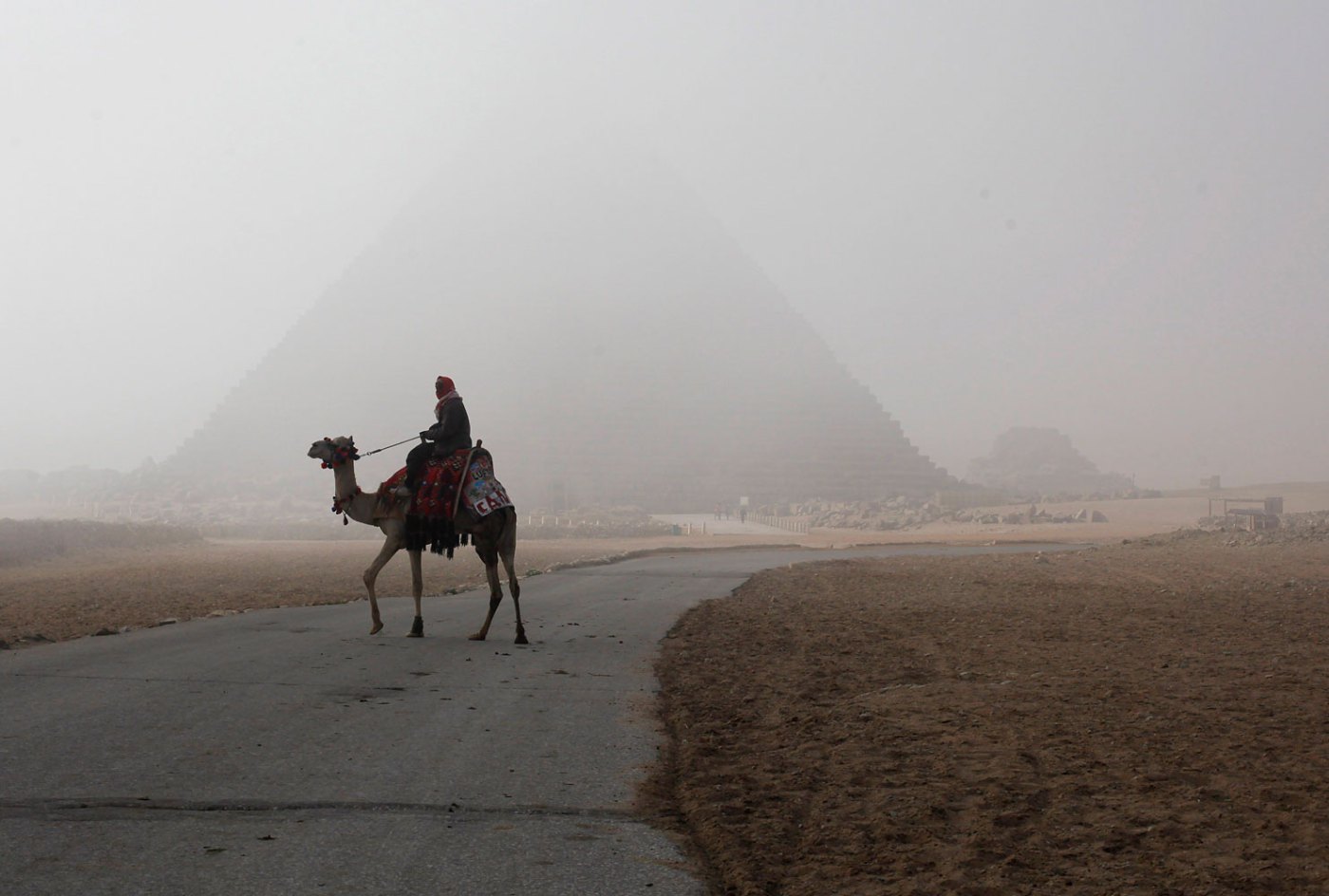 A man rides his camel as he waits for tourists at the Giza pyramids area, south of Cairo, Feb. 20, 2014.