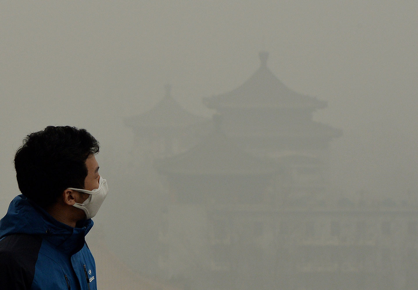 A tourist wearing a face mask climbs Jingshan Hill beside the Forbidden City as heavy air pollution continues to shroud Beijing on Feb. 26, 2014.