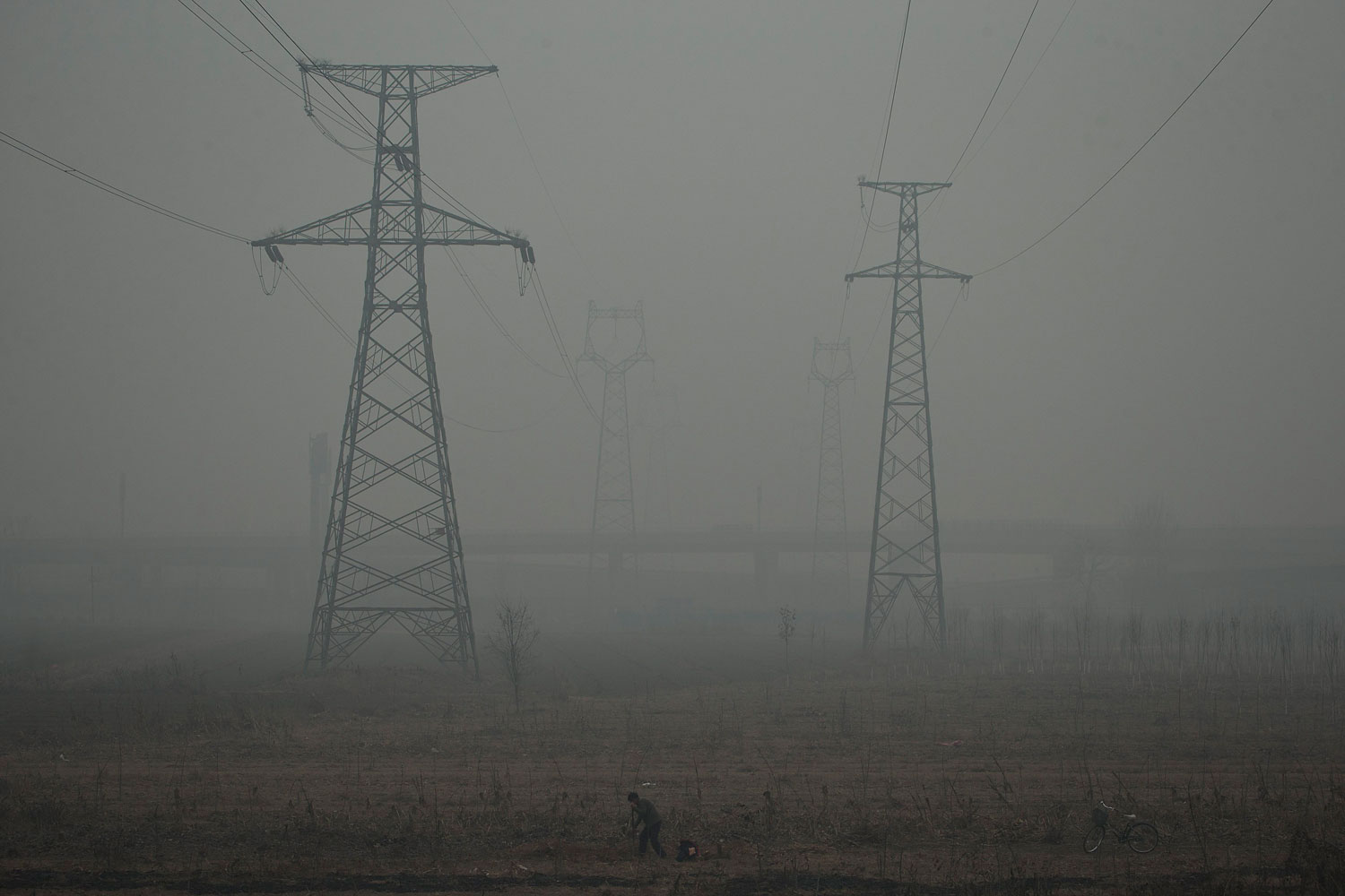 A farmer shovels in a field near electric pylons in heavy haze on a severely polluted day in Shijiazhuang, in northern China's Hebei province, Feb. 26, 2014.