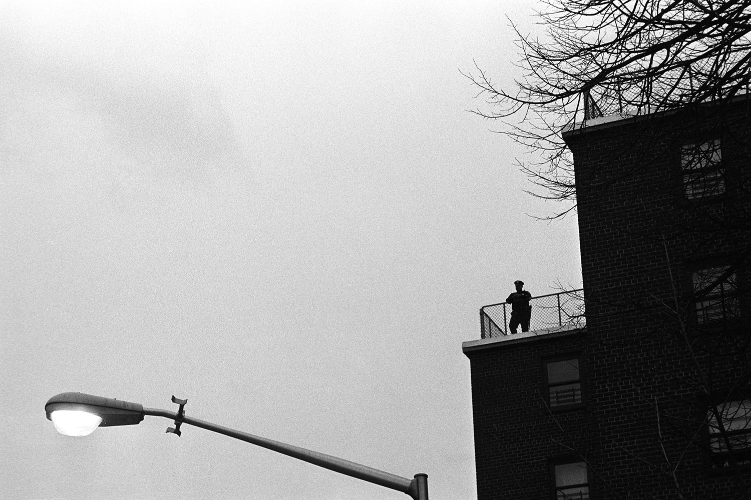 A police officer patrols rooftops of the public housing projects. Summer Housing Public Housing Projects, Bedford Stuyvesant, Brooklyn, NY, 2005.