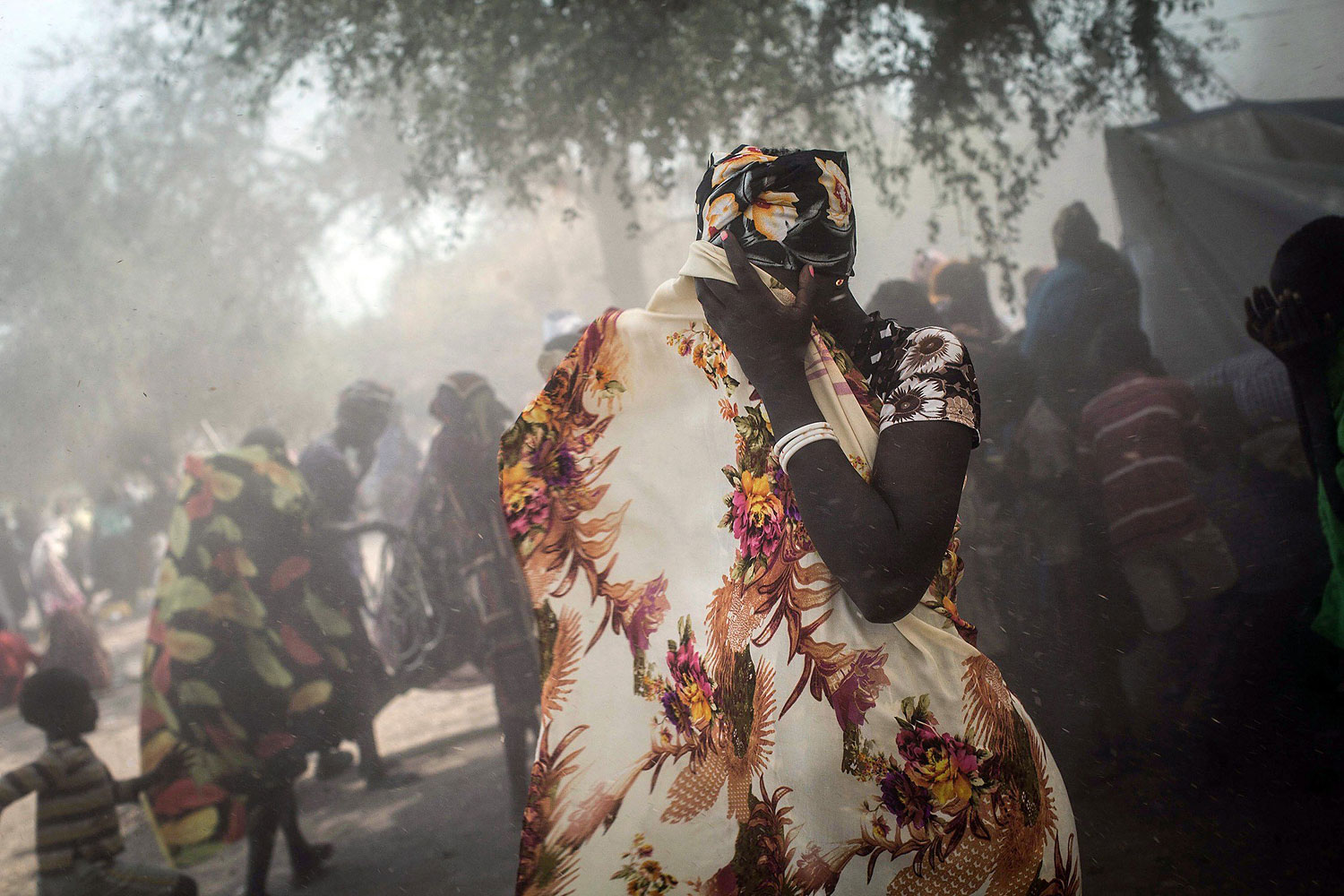 A woman covers her face as a UN helicopter takes off from Minkammen, where people receive food aid and other items from a recent International Committee of the Red Cross delivery on Jan. 8, 2014.