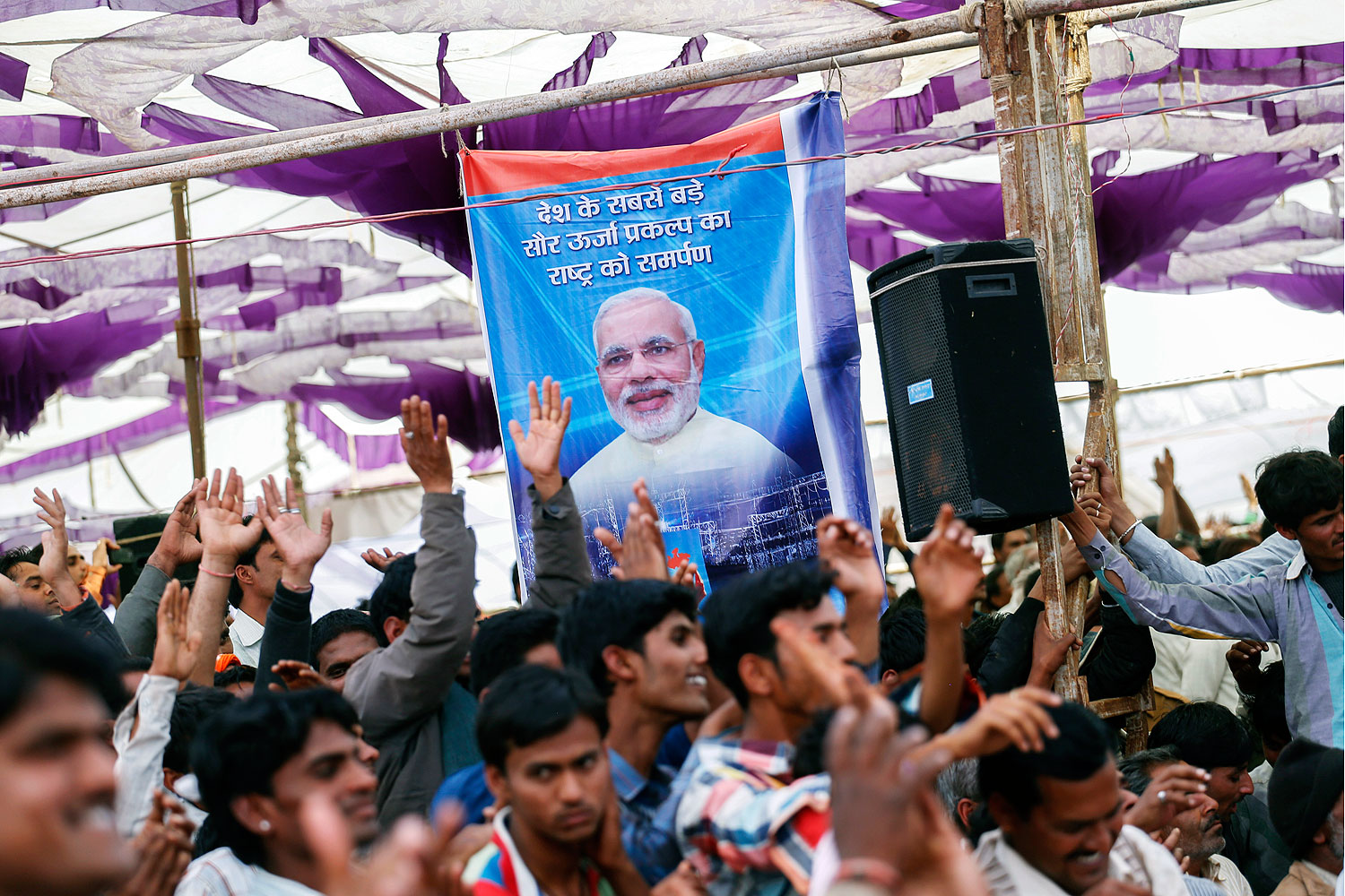 Supporters cheer beneath a poster featuring Narendra Modi at a rally near Bhagwanpura, Madhya Pradesh, India, on Feb. 26, 2014 (Bloomberg / Getty Images)
