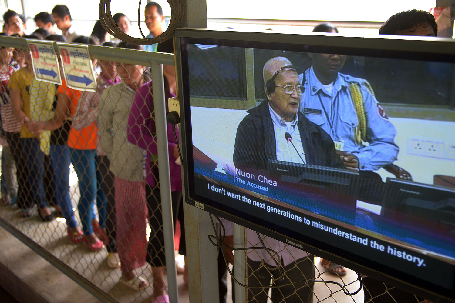 Former Cambodian Khmer Rouge leader "Brother Number Two" Nuon Chea is seen on a television screen (R) as people (L) line up to attend the trial of former Khmer Rouge leaders at the Extraordinary Chamber in the Courts of Cambodia (ECCC) in Phnom Penh in Oct. 2013 (Tang Chhin Sothy—AFP/Getty Images)
