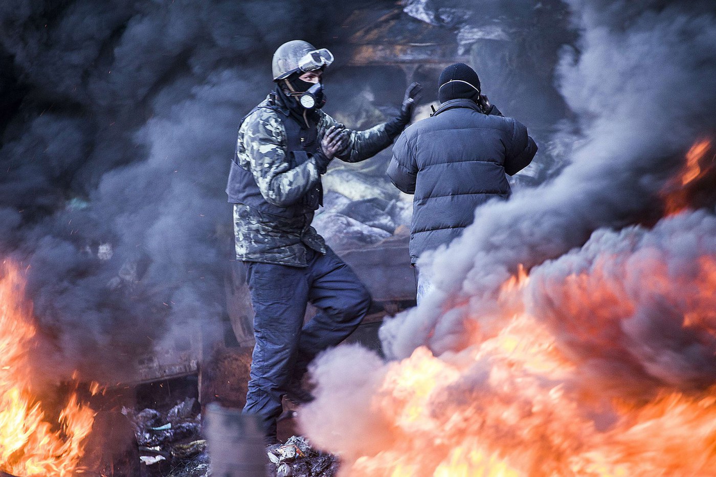 Anti-government demonstrators stand among the smoke of burning barricades during clashes with riot police in Kiev, February 18, 2014.