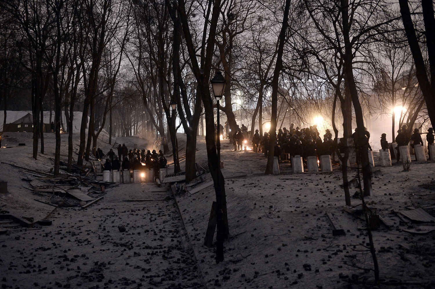 Riot police stand guard opposite anti-government protesters in a park area near a road block in Kiev on Jan. 28, 2014.
