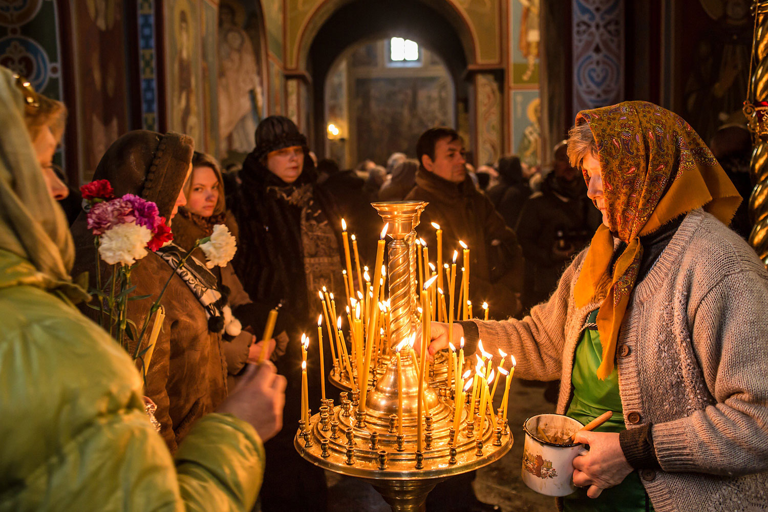 Women light candles inside Mikhailovsky Cathedral before a memorial service for Mikhail Zhiznevsky, 25, an anti-government protester who was killed in clashes with police on January 26, 2014 in Kiev.