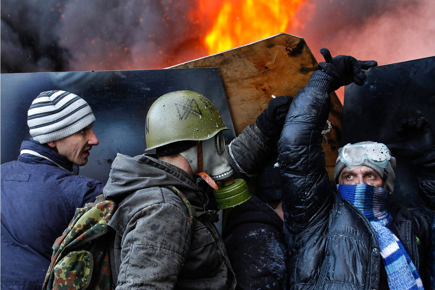 Pro-European integration protesters take cover from water sprayed from a fire engine at the site of clashes with riot police in Kiev, Jan. 23, 2014.