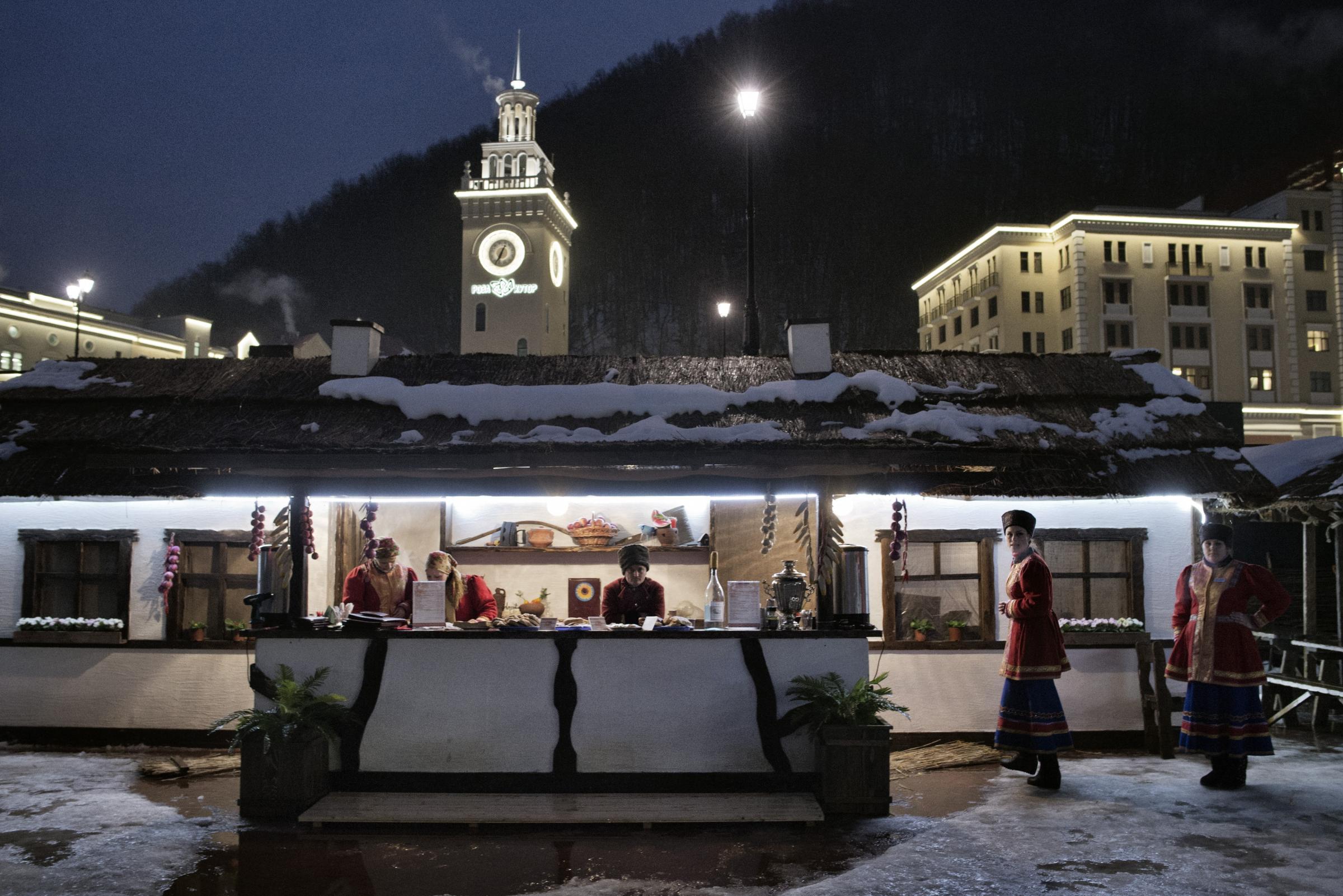 Sochi Russia January  17 2014 Workers wait for clients at the borsht bar erected in the center of Roza Khutor, the skiing village that will serve as a key venue for the Winter Olympic Games in Sochi. Dressed in traditional Cossack uniforms and serving up carafes of stiff Russian moonshine, the eatery injects a touch of local culture Ðand kitsch Ð into the otherwise staid and sleek atmosphere of Roza Khutor.
