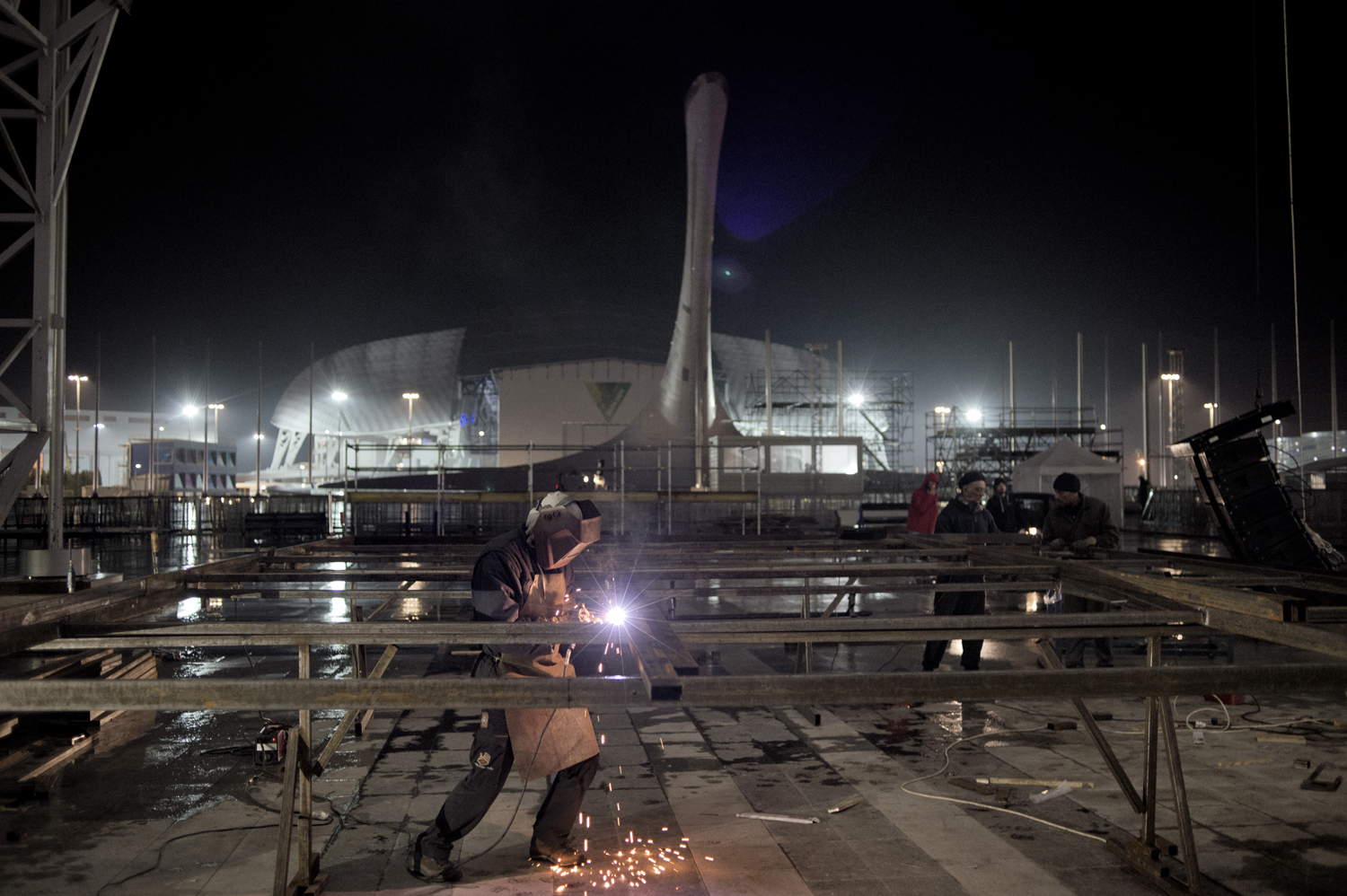 Sochi Russia January 17 2014A welder assembles the frame for the winners' podium of the Winter Olympic Games to be held in Sochi. In the background hovers the massive Olympic torch, which will be lit during the opening ceremony for the Sochi Games on Feb. 7.