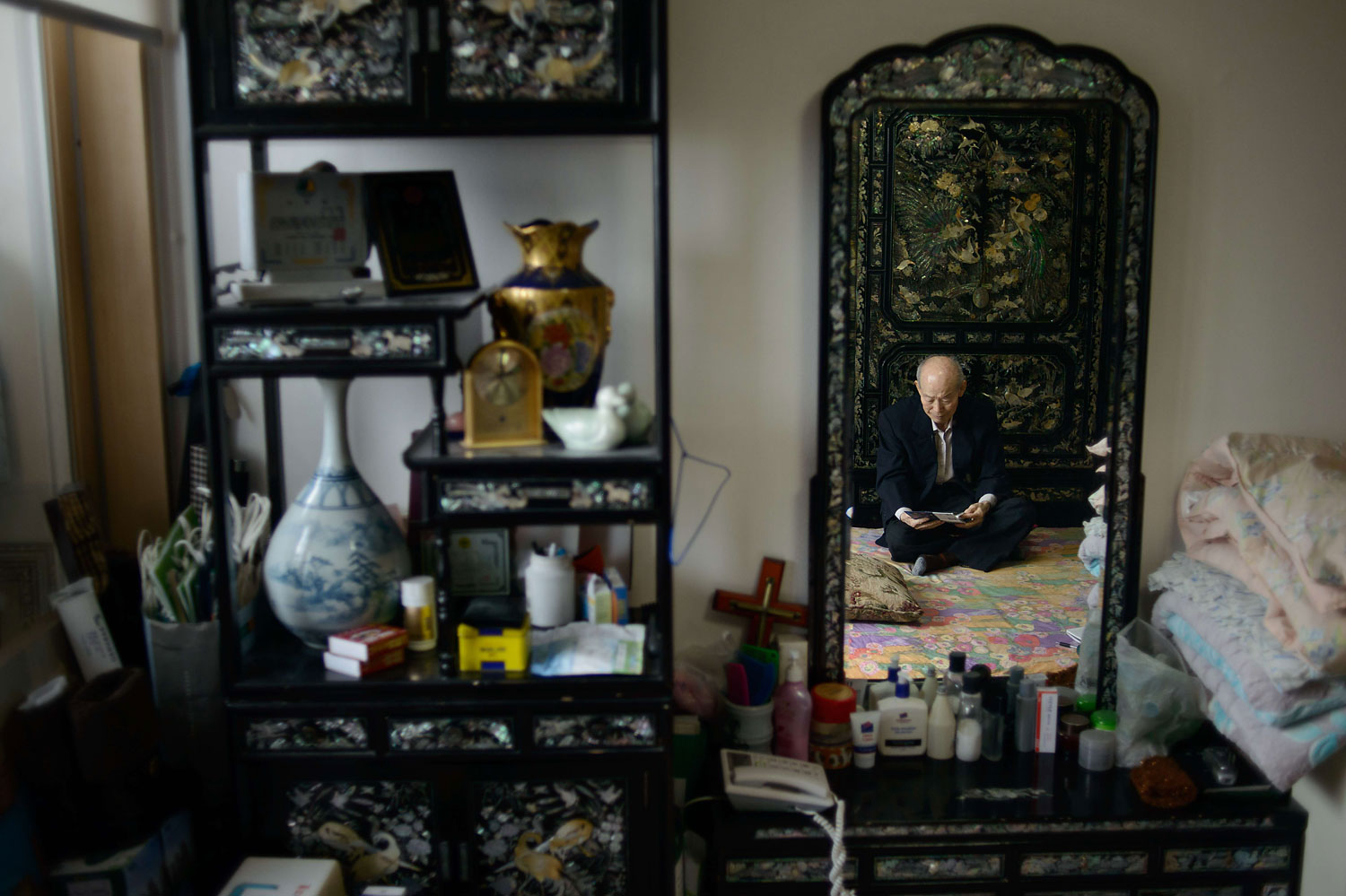 North Korean-born Kim Se-Rin sits in the bedroom of his home on the outskirts of Seoul, on Feb. 17, 2014, as he looks at photos of his South Korean family members that he plans to give to his North Korean relatives whom he had not seen for 60 years.