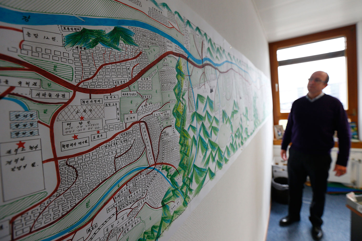 A United Nations Human Rights staff stands in front of a drawing illustrating North Korean labour camp no 18 in Geneva Feb. 17, 2014 (Denis Balibouse—Reuters)