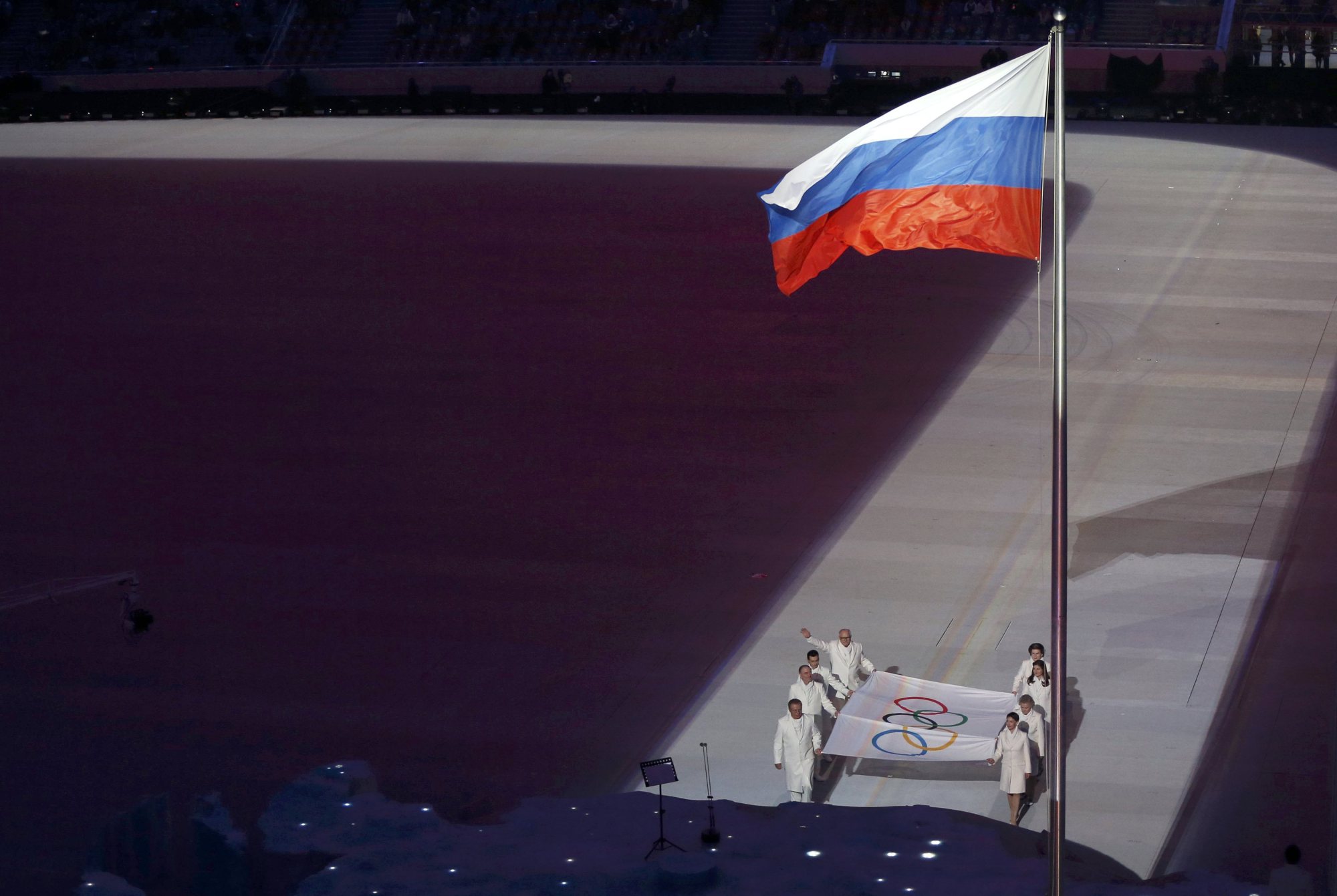 The Olympic flag is paraded past the Russian flag.