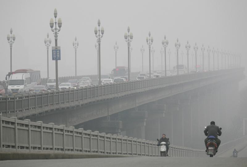 People ride along a bridge on a smoggy day in Nanjing