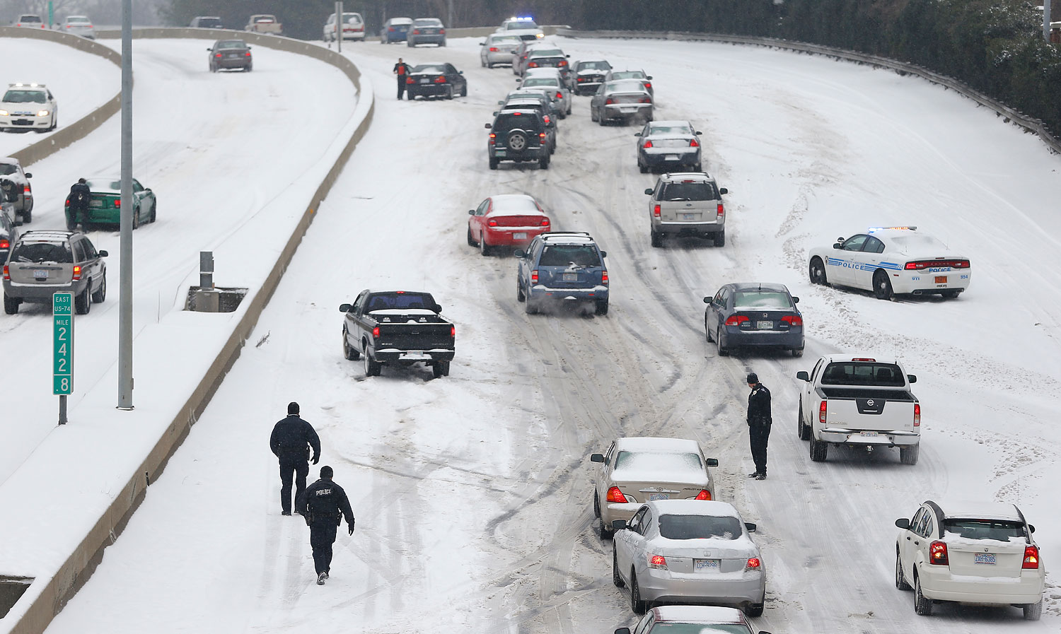 Charlotte Mecklenburg Police Officers work to assist motorists as they attempt to drive up a hill that is covered in snow in Charlotte, North Carolina Feb. 12, 2014. (Chris Keane / Reuters)