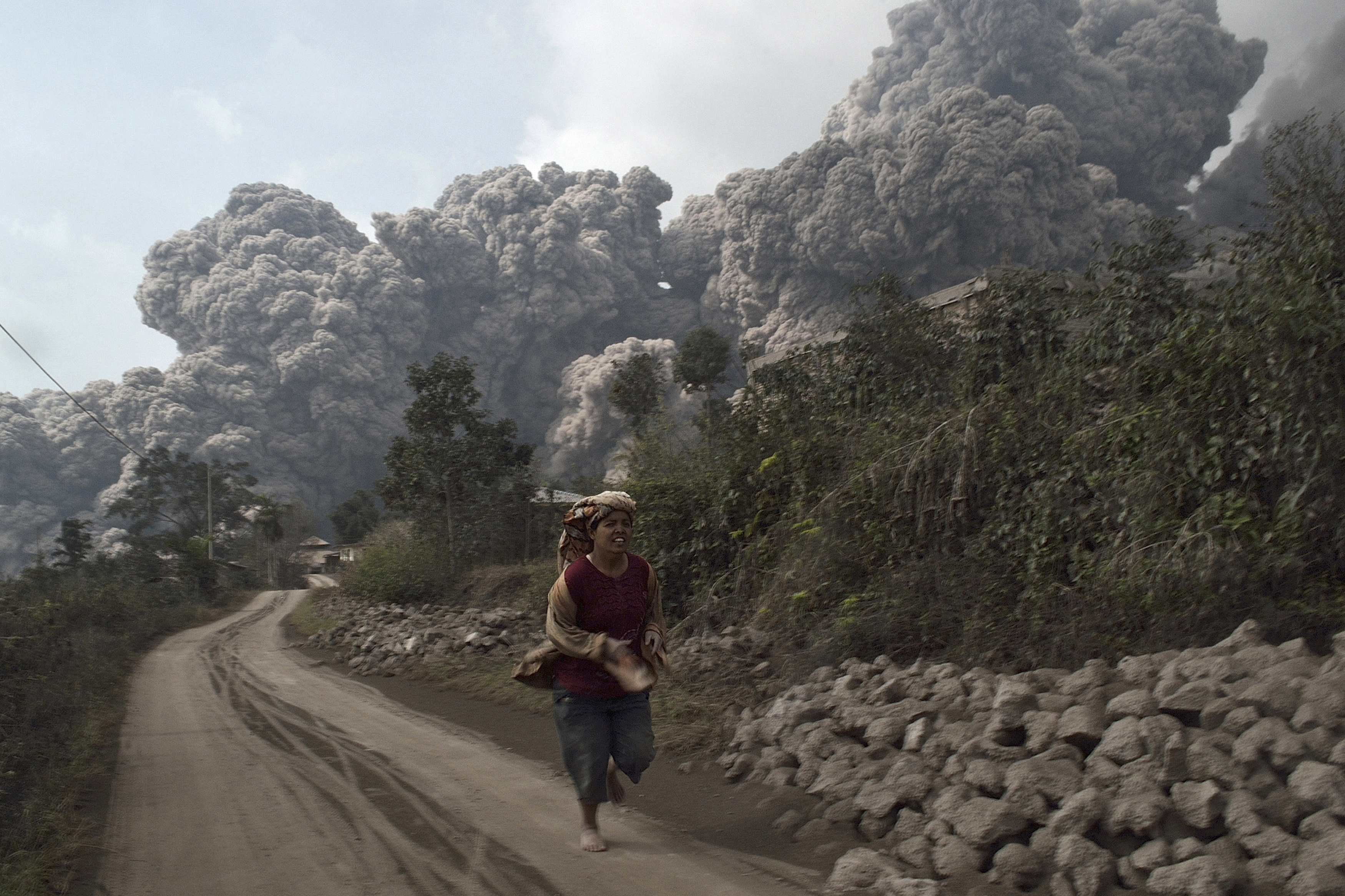 A villager run as Mount Sinabung erupt at Sigarang-Garang village in Karo district