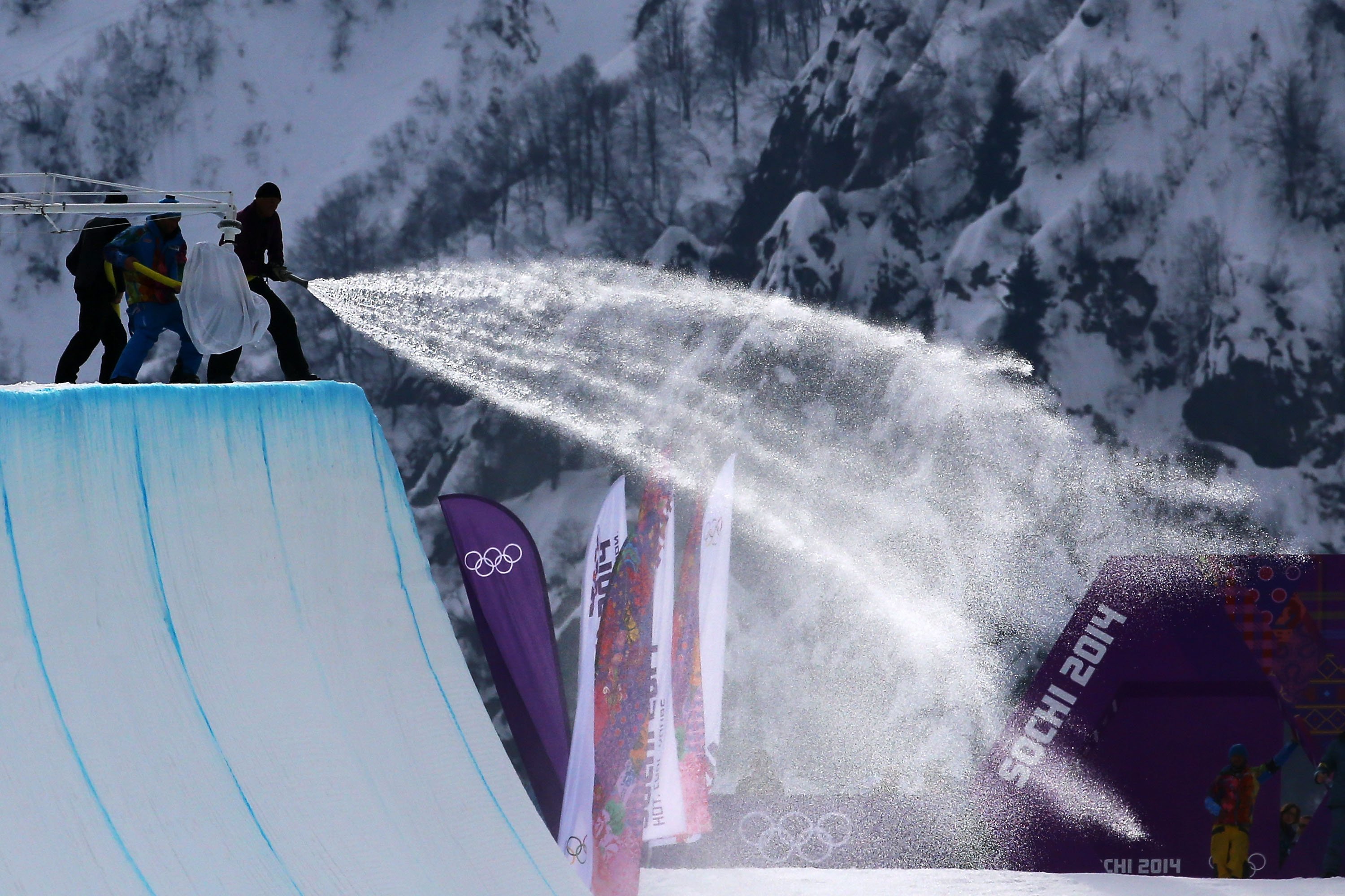 Workers spray down the halfpipe before competition begins in the Snowboard Men's Halfpipe Qualification Heats.