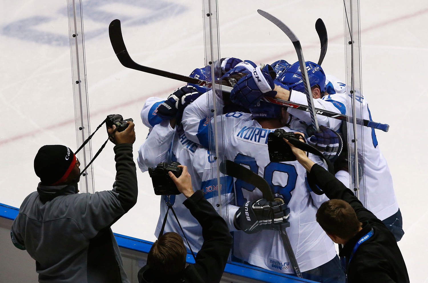 Photographers capture the celebration of Finland's Teemu Selanne and his linemates after he scored against Team USA during the second period of their men's ice hockey bronze medal game.
