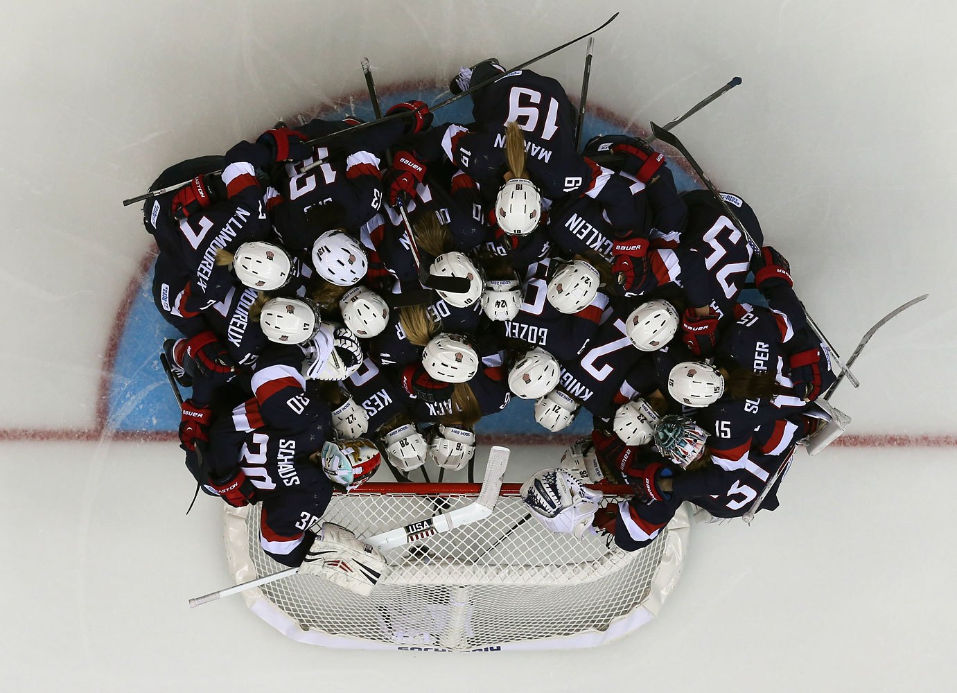 Members of USA's women's ice hockey team huddle around USA's goalie Molly Schaus before their women's preliminary round hockey game against Switzerland at the Sochi 2014 Winter Olympic Games Feb. 10, 2014.